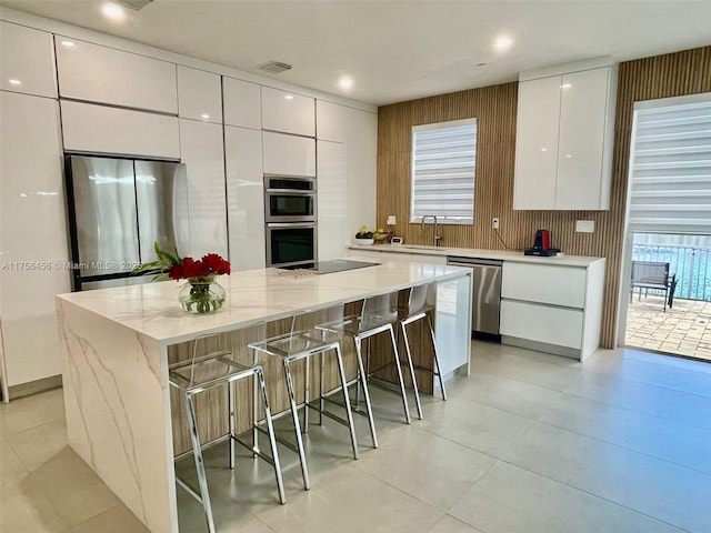 kitchen with a breakfast bar, modern cabinets, white cabinetry, and stainless steel appliances