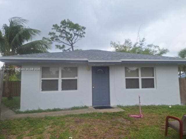 view of front of house with fence, a front lawn, and stucco siding