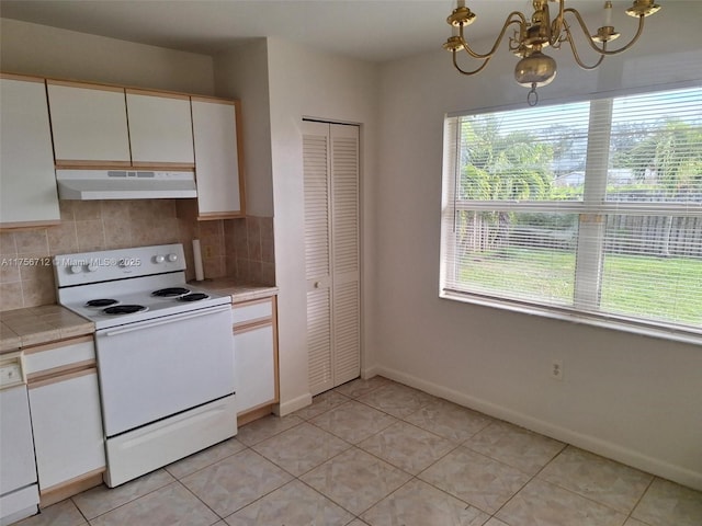 kitchen with white appliances, white cabinets, an inviting chandelier, under cabinet range hood, and backsplash