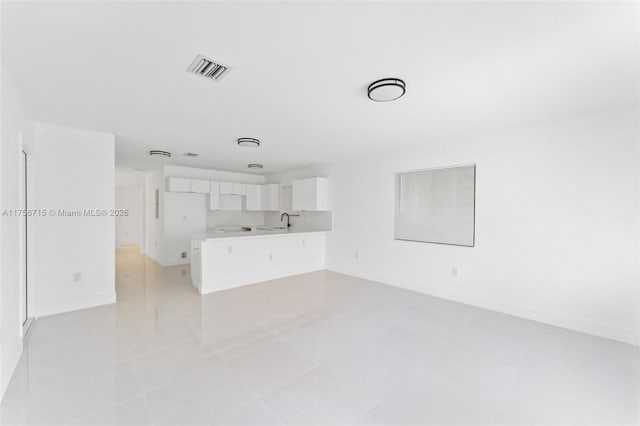 unfurnished living room featuring visible vents, a sink, baseboards, and light tile patterned flooring