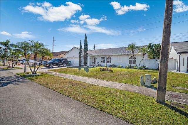 single story home with a front lawn, fence, stucco siding, a garage, and driveway