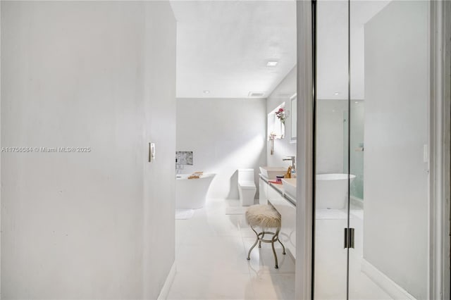 full bathroom featuring baseboards, a soaking tub, vanity, and tile patterned flooring
