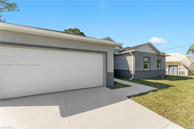 single story home with an attached garage, driveway, a front yard, and stucco siding