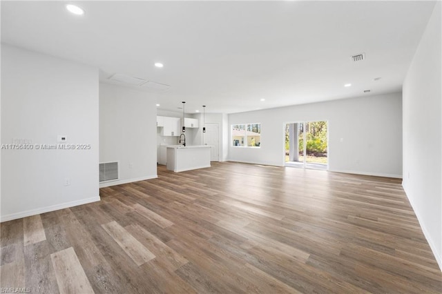 unfurnished living room with light wood finished floors, baseboards, visible vents, and recessed lighting