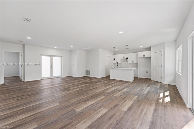 unfurnished living room featuring recessed lighting, visible vents, wood finished floors, and french doors