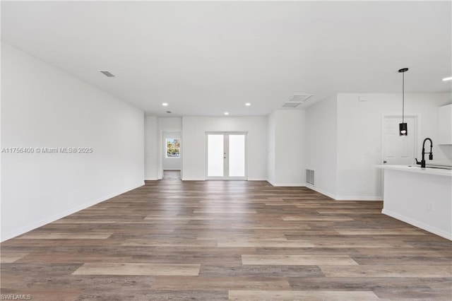 unfurnished living room featuring recessed lighting, french doors, visible vents, and wood finished floors