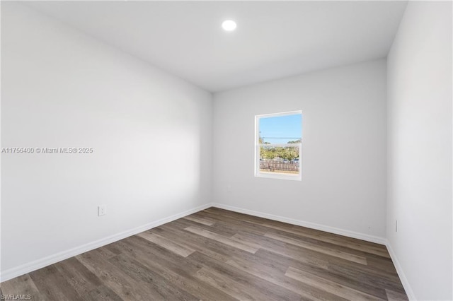 empty room with dark wood-type flooring, recessed lighting, and baseboards