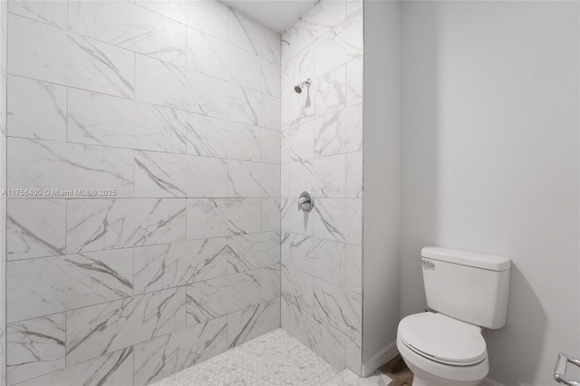 full bathroom with toilet, baseboards, and tiled shower