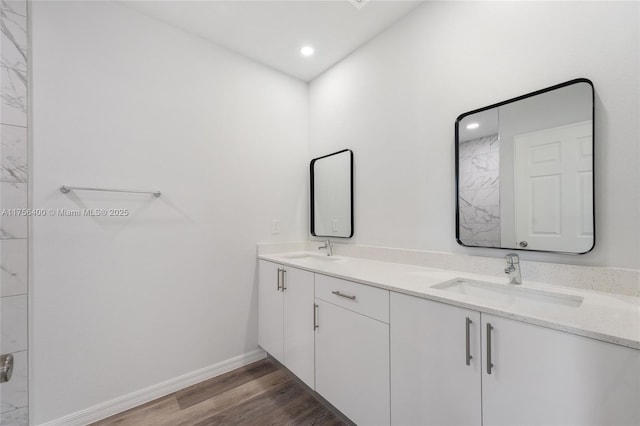 bathroom featuring double vanity, a sink, baseboards, and wood finished floors