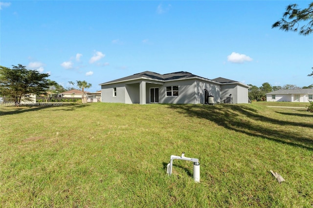 rear view of property featuring a lawn and stucco siding