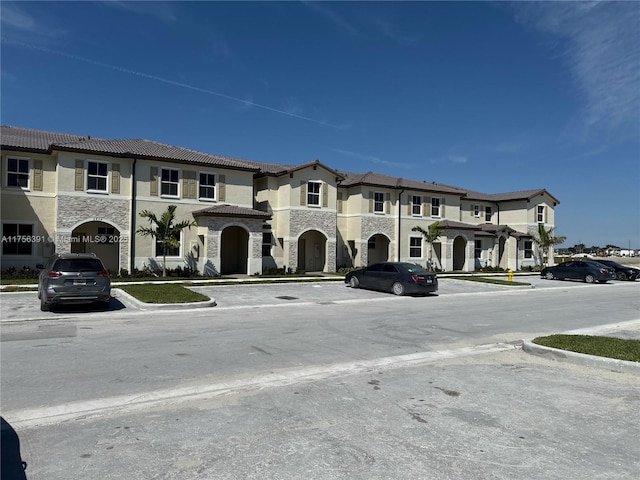 view of front of property with stone siding, a tile roof, and stucco siding