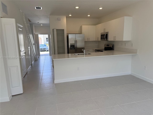 kitchen featuring stainless steel appliances, light countertops, a sink, and visible vents