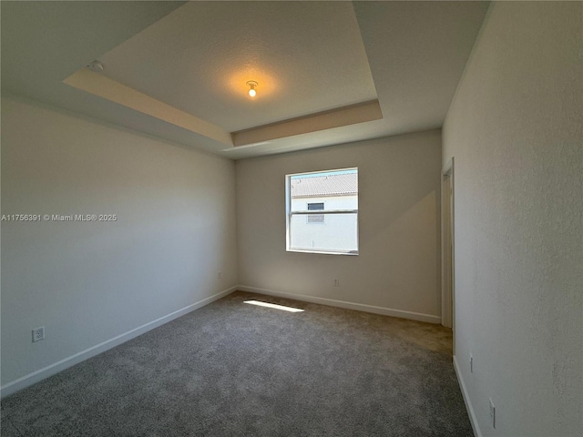 unfurnished room featuring carpet, baseboards, and a raised ceiling