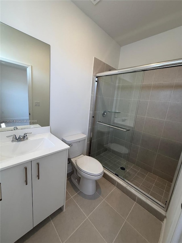 bathroom with vanity, a shower stall, toilet, and tile patterned floors