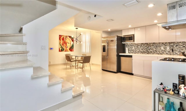 kitchen featuring light countertops, hanging light fixtures, decorative backsplash, appliances with stainless steel finishes, and ventilation hood