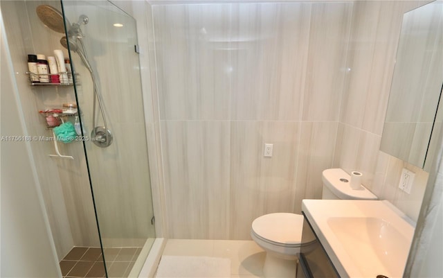 bathroom with a stall shower, vanity, toilet, and tile walls