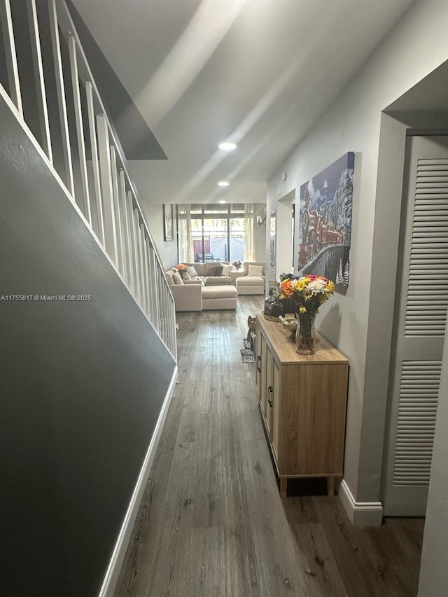 corridor featuring stairs, wood finished floors, and baseboards