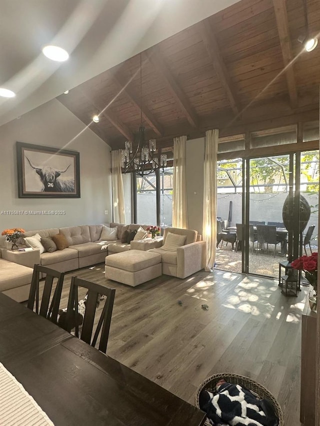 living area with a wealth of natural light, wood finished floors, vaulted ceiling with beams, and an inviting chandelier