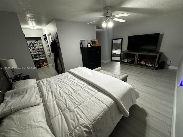 bedroom featuring light wood-type flooring, visible vents, a textured ceiling, and baseboards