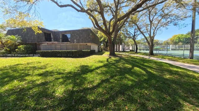 view of yard with a tennis court and fence