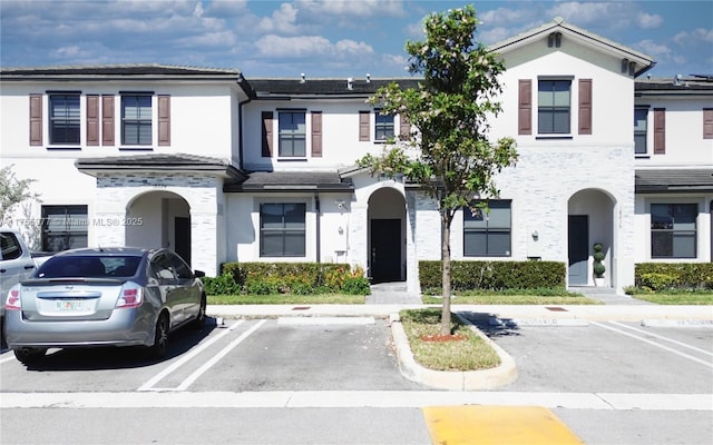 view of property with uncovered parking and stucco siding