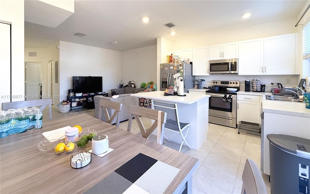 kitchen featuring stainless steel appliances, a kitchen island, a sink, visible vents, and light countertops