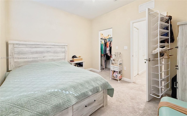 carpeted bedroom featuring a walk in closet, a closet, visible vents, and baseboards