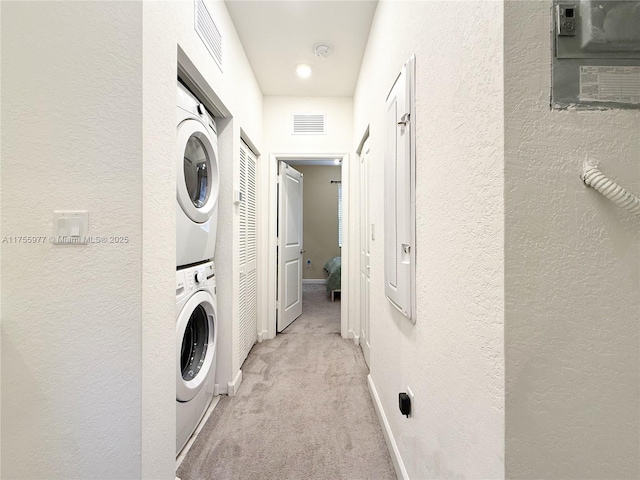 laundry room with light carpet, laundry area, visible vents, and stacked washer / drying machine