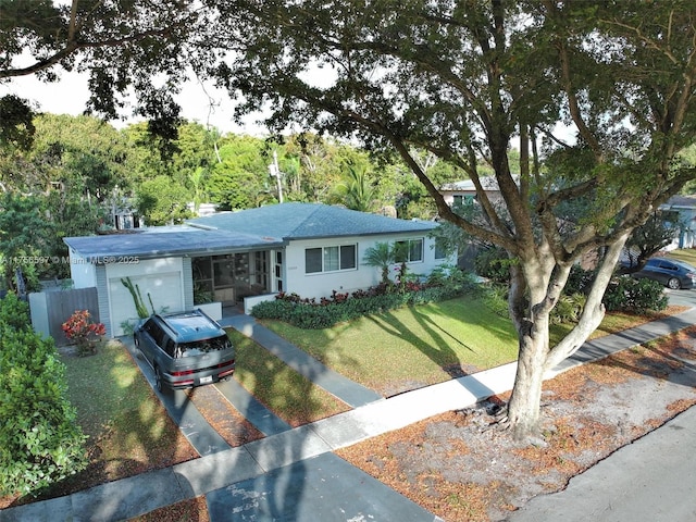 ranch-style home with a front yard, driveway, fence, and a garage