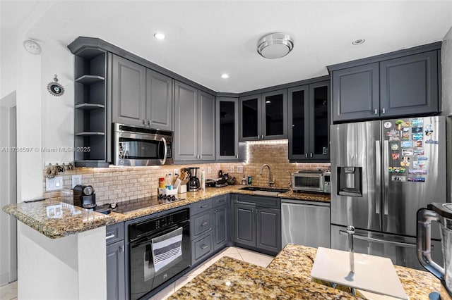 kitchen with tasteful backsplash, light stone countertops, black appliances, open shelves, and a sink