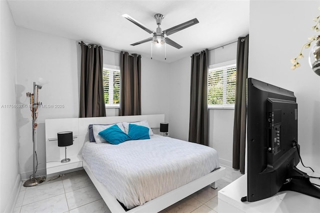 bedroom with ceiling fan, multiple windows, and baseboards