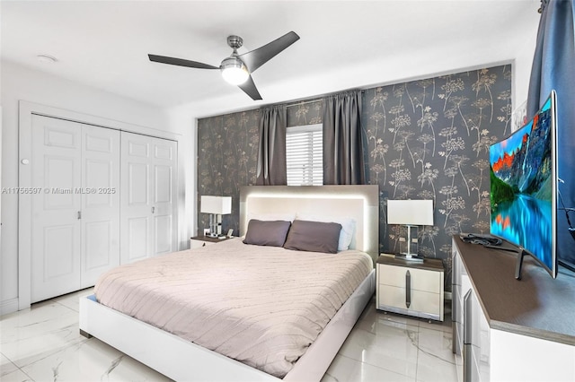 bedroom featuring ceiling fan, marble finish floor, a closet, and wallpapered walls