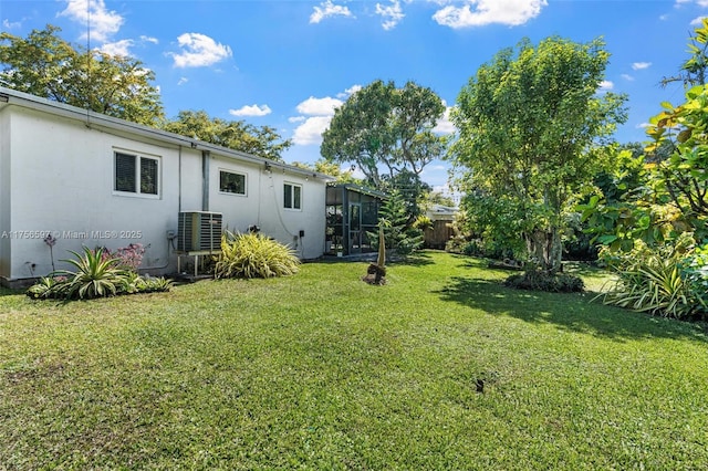 view of yard with central AC unit, glass enclosure, and fence