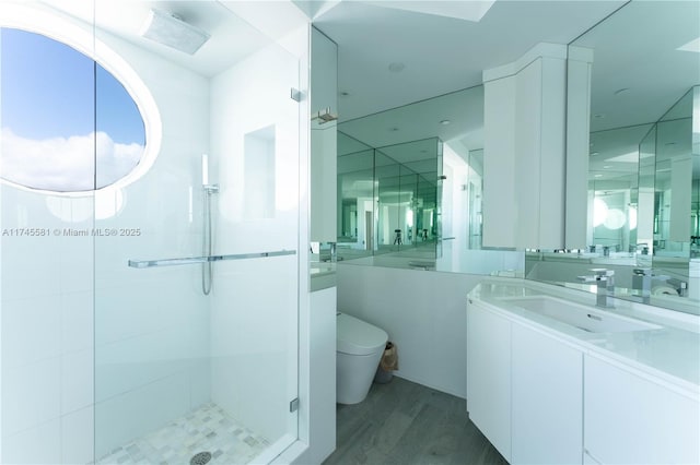 bathroom with vanity, wood finished floors, a shower stall, and toilet