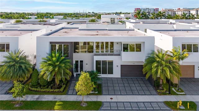 modern home featuring decorative driveway, an attached garage, and stucco siding