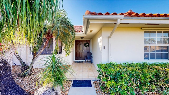 doorway to property featuring a tiled roof and stucco siding