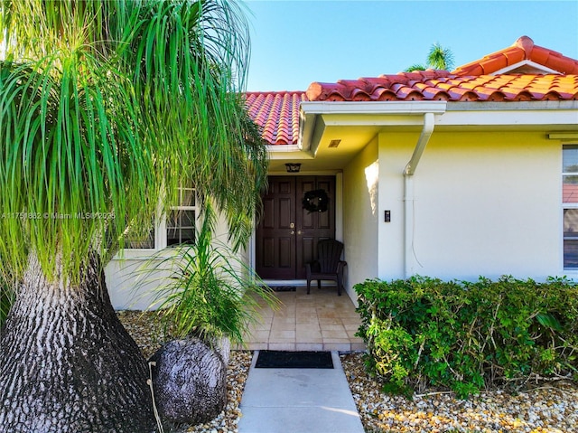 property entrance with stucco siding and a tiled roof