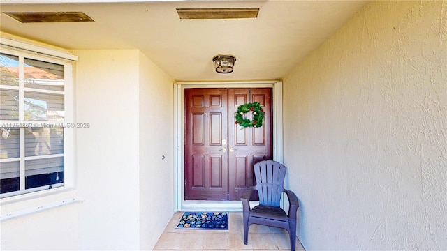 view of exterior entry featuring visible vents and stucco siding