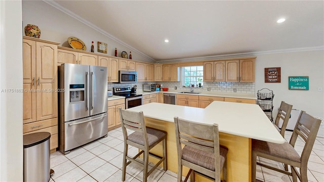 kitchen with a kitchen bar, appliances with stainless steel finishes, a sink, and light brown cabinetry