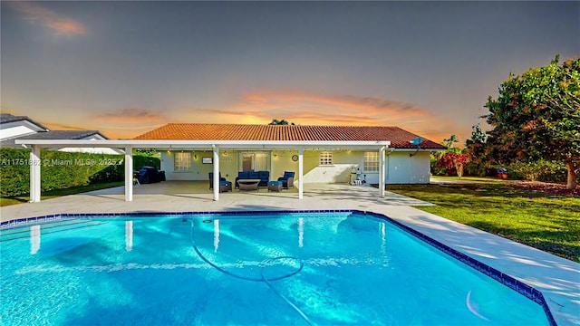 exterior space with a patio, an outdoor pool, a yard, a tiled roof, and stucco siding