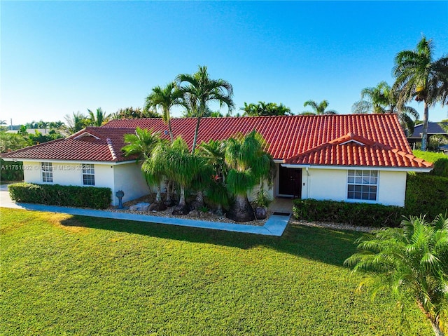 mediterranean / spanish-style home featuring a tile roof, a front lawn, and stucco siding