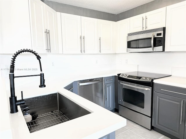 kitchen with appliances with stainless steel finishes, a sink, and white cabinetry