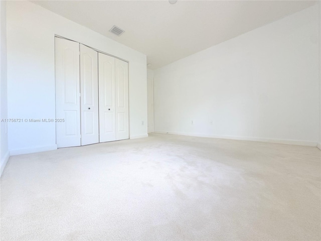 unfurnished bedroom with baseboards, a closet, visible vents, and light colored carpet