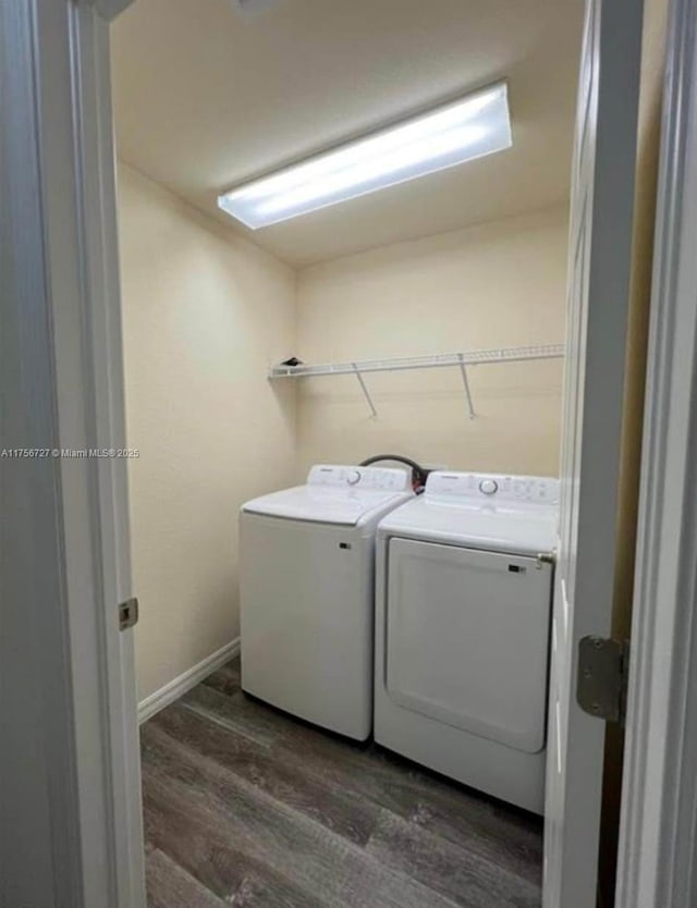 washroom featuring laundry area, baseboards, separate washer and dryer, and wood finished floors