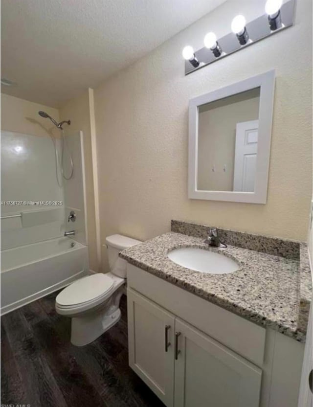 bathroom featuring a textured ceiling, toilet, wood finished floors, bathing tub / shower combination, and vanity