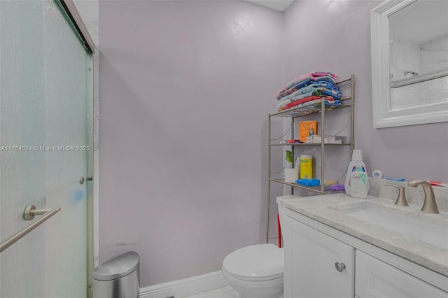 bathroom featuring baseboards, a shower with shower door, vanity, and toilet