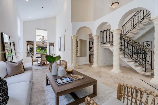 living area with ornate columns, a high ceiling, baseboards, and an inviting chandelier