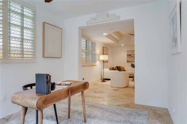 office area with a ceiling fan and a tray ceiling