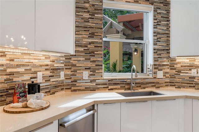 kitchen with tasteful backsplash, modern cabinets, a sink, and white cabinets