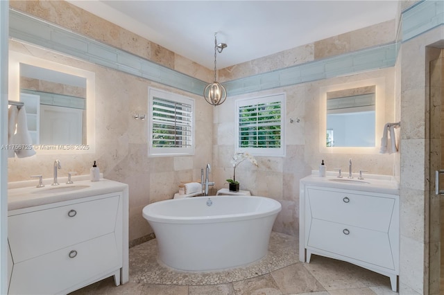 bathroom featuring a soaking tub, tile walls, two vanities, and a sink